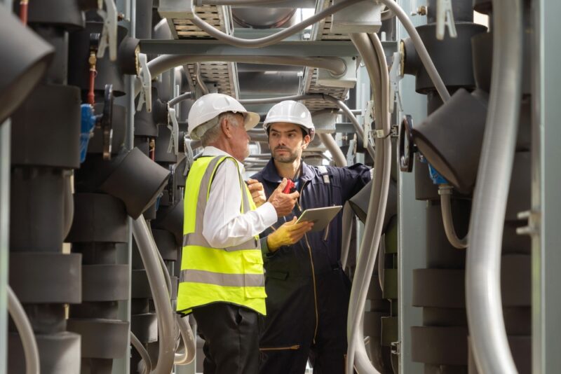 Dva inženjera u zaštitnoj opremi proveravaju industrijske instalacije i cjevovode tokom održavanja sistema